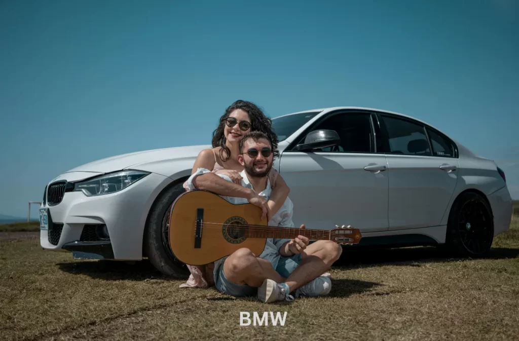 Couple relaxing with their BMW car in the background.