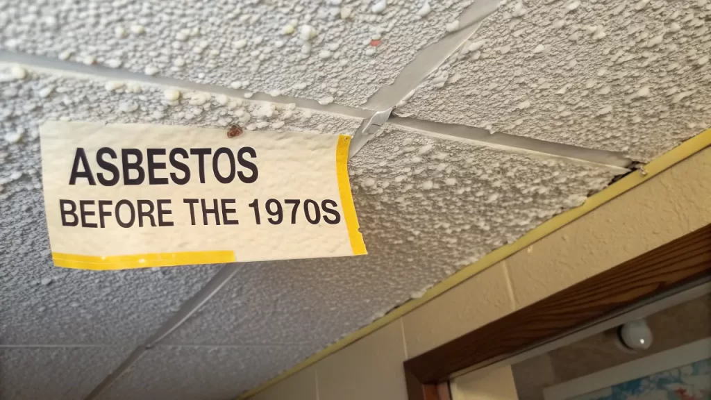 Warning sign showing popcorn ceiling containing asbestos installed before the 1970s.